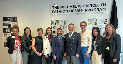 A group of nine people standing in front of a sign for the Michael W. Faircloth Fashion Design Program