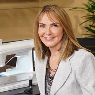 Peggy Sagers is facing forward and smiling. She has brown hair and wears a beige jacket.